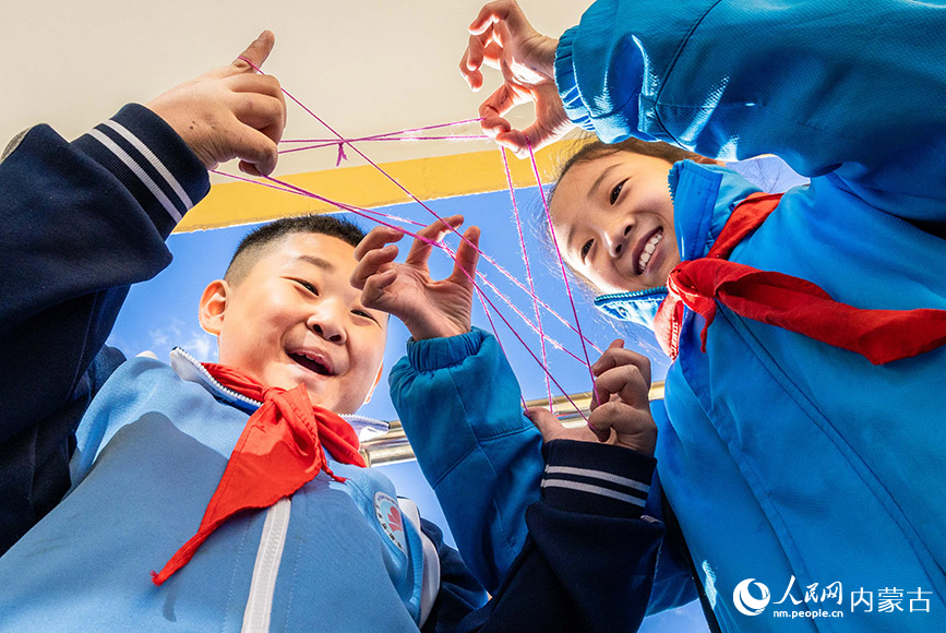11月27日,呼和浩特市玉泉区清泉街小学的学生利用课间时间玩翻花绳。丁根厚摄