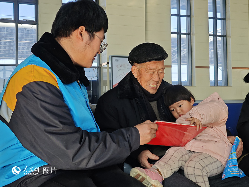 1月26日，春运首日，中国铁路沈阳局集团有限公司长春车务段德惠西站青年志愿者为旅客赠送春联福字。人民网记者 王海跃摄