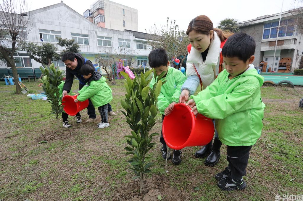 3月11日,江苏省苏州市姑苏区新庄社区志愿者带着小朋友一起参加义务植树活动。新华社发(杭兴微摄)