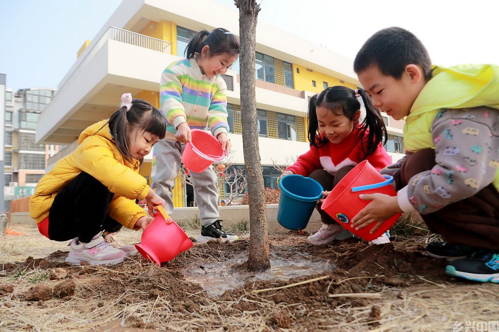 3月11日,在山东省高密市凤鸣实验幼儿园,孩子们为树木浇水。新华社发(李海涛摄)