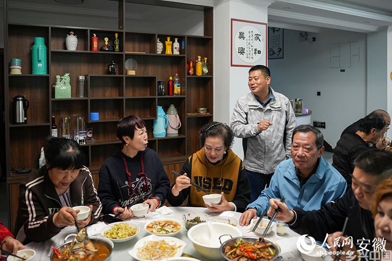 和坪山庄民宿负责人汪建同用餐的游客交流。人民网记者 王锐摄