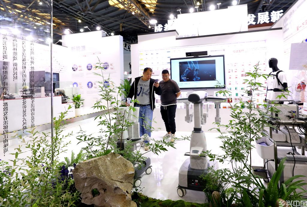 5月12日，参观者在江苏苏州展台的一组医疗机器人展品前驻足观看。