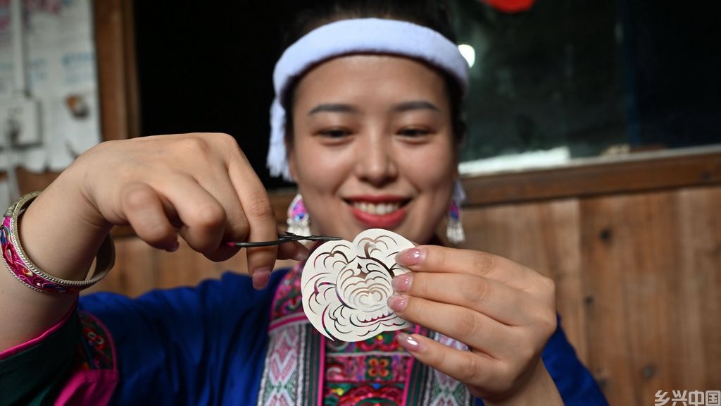 在广西三江侗族自治县同乐苗族乡同乐村寨从屯，侗族刺绣传承人韦丽姣在剪纸制作绣品图案（8月30日摄）。