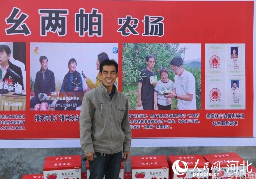 杨增林站在自己家农场广告牌前，职称证书成卖点。人民网记者 祝龙超摄