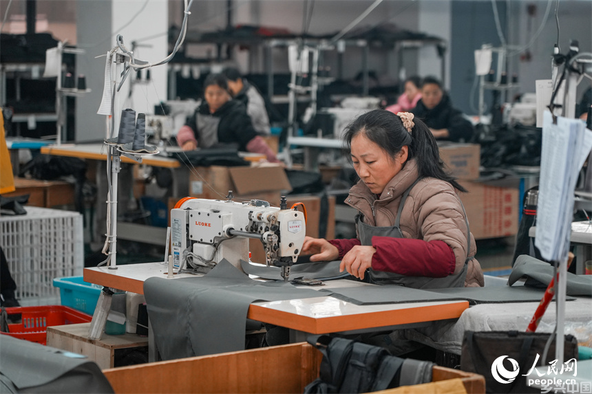 工人们正在缝合行李箱里布。人民网 涂诗轩摄