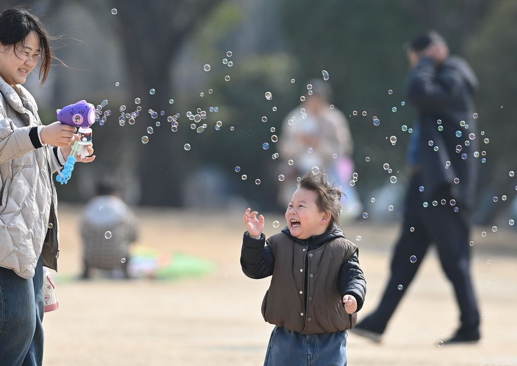 3月9日，家长和孩子在山东省滕州市一处公园玩泡泡。新华社发（李志军摄）