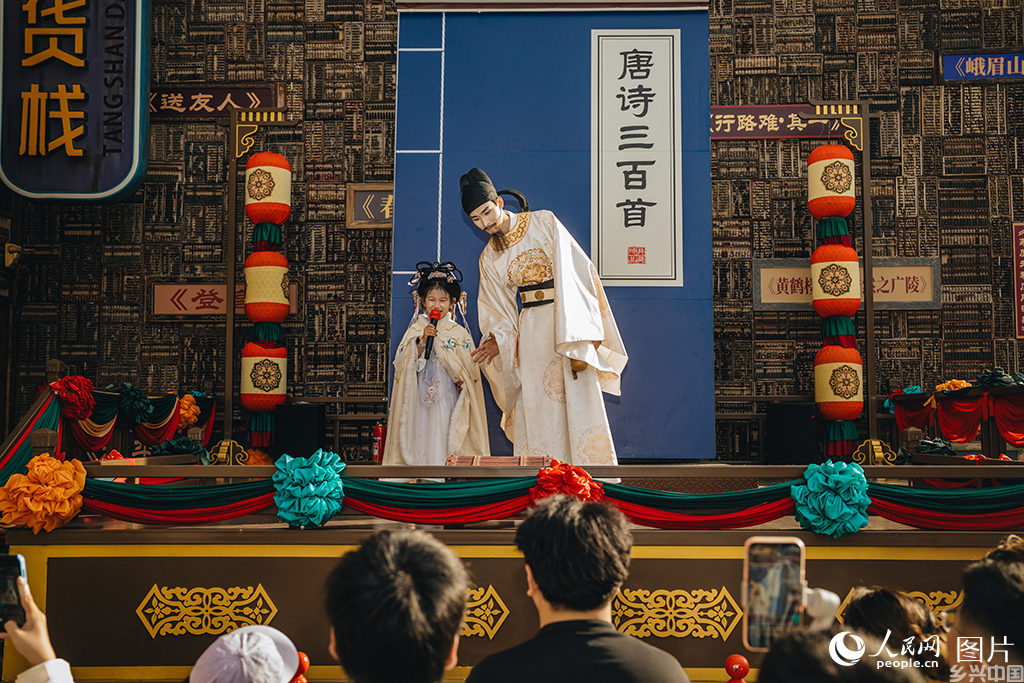 2026年5月18日，河北唐山河头老街的NPC演员“李白”正与小游客吟诗互动。人民网记者 商帆摄